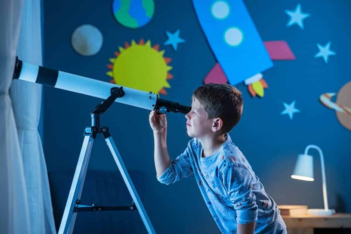 Garçon observant les étoiles la nuit avec un télescope