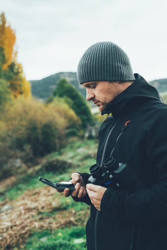 Un jeune homme avec des jumelles à la montagne.